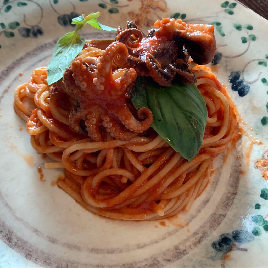 Spaghetti with baby octopus and red datterino tomato sauce with basil
